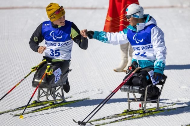 Chinese athlete Liu Mengtao (right) and German athlete Martin Fleig greet each other with a fist bump after the Para biathlon men’s middle distance sitting competition at the Beijing 2022 Paralympic Winter Games, March 8, 2022. (Photo by Weng Qiyu/People’s Daily Online)