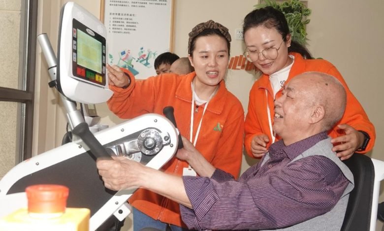 Employees of an intelligent nursing home in Anboxin neighborhood, southwest China’s Chongqing municipality instruct a senior citizen to use smart medical equipment, Oct. 14, 2021. (Photo by Cao Yonglong/People’s Daily Online)
