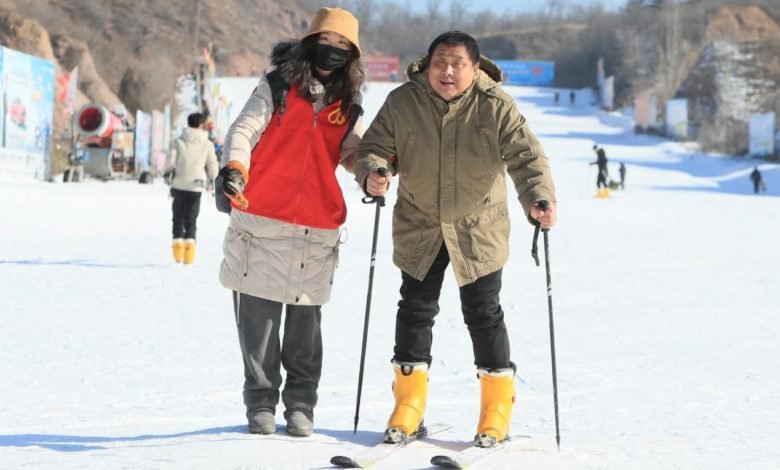 A person with disabilities learns to ski with the help of a volunteer in Chaoyang city, northeast China’s Liaoning province, Jan. 20, 2022. (Photo by Qiu Yijun/People’s Daily Online)