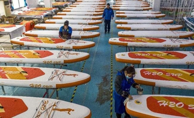 Workers are busy making surfboards for overseas orders at a company in Lujiang county, Hefei city, east China’s Anhui province, Feb. 14, 2022. (Photo by Zuo Xuechang/People’s Daily Online)